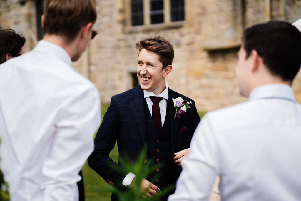 Groom smiling while talking to groomsmen at wedding reception