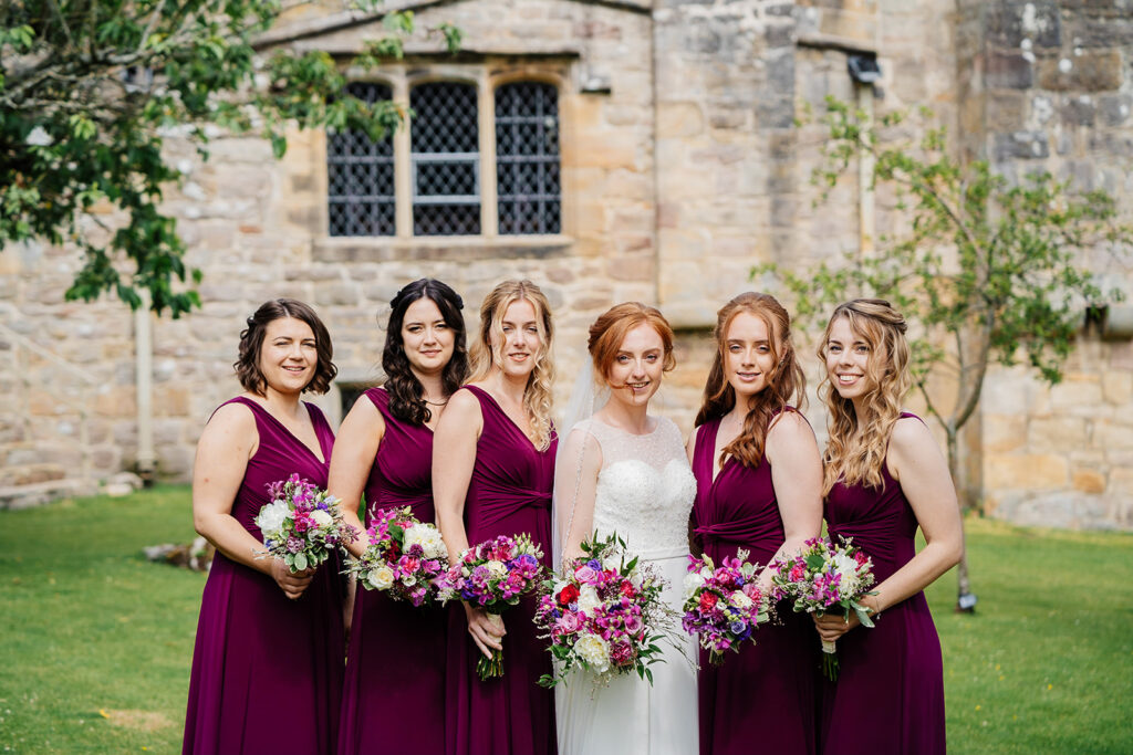 Bridesmaids in purple dresses with bouquets at a wedding