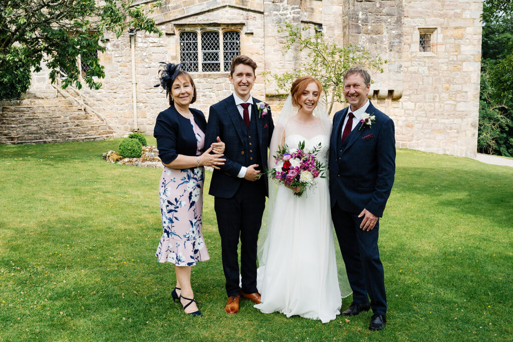 Bride and groom with parents in a garden ceremony setting