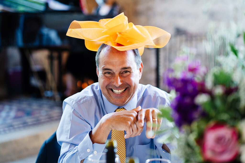 Man smiling with bright orange hat at lively indoor event