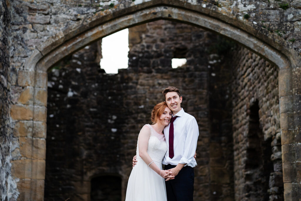 Couple embracing by ancient stone ruins on wedding day