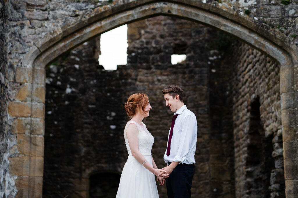Couple holding hands in front of historic stone building