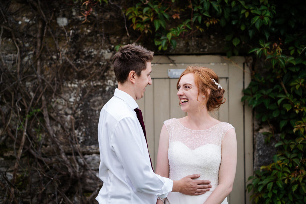Bride and groom sharing a joyful moment outside. The Priests House in Barden, North Yorkshire