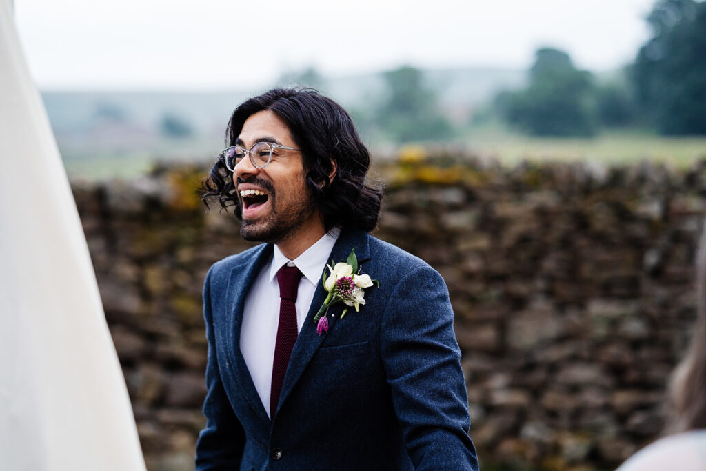 Smiling man in a suit at outdoor event with stone wall background