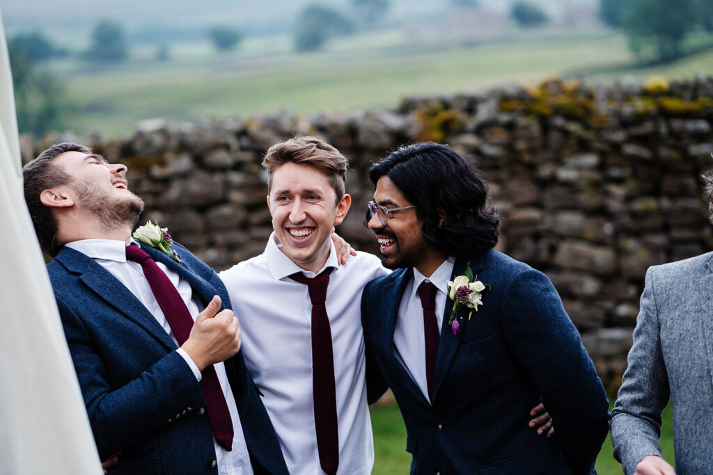 Men in suits laughing at a joyful outdoor gathering