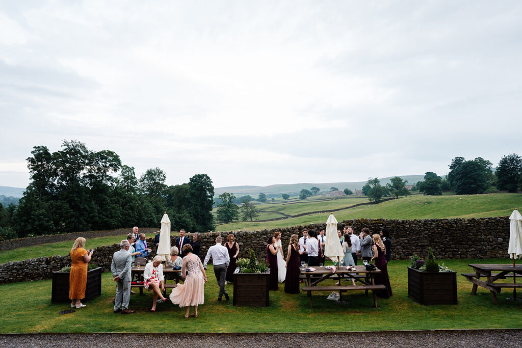 Outdoor wedding guests enjoying scenic countryside setting