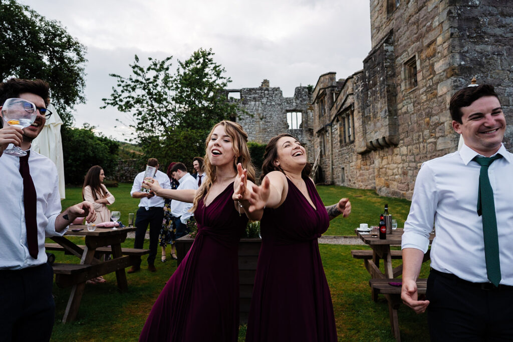 People enjoying an outdoor wedding celebration at a historic venue. The Priests House in Barden, North Yorkshire