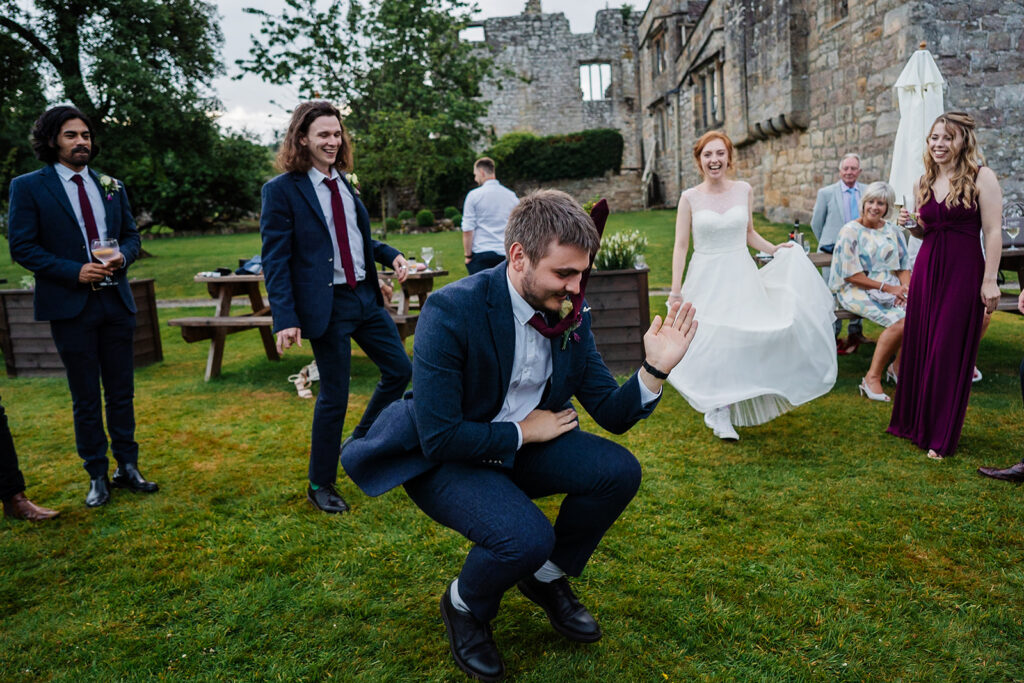 Wedding guests dancing and celebrating outdoors in formal attire The Priests House in Barden, North Yorkshire