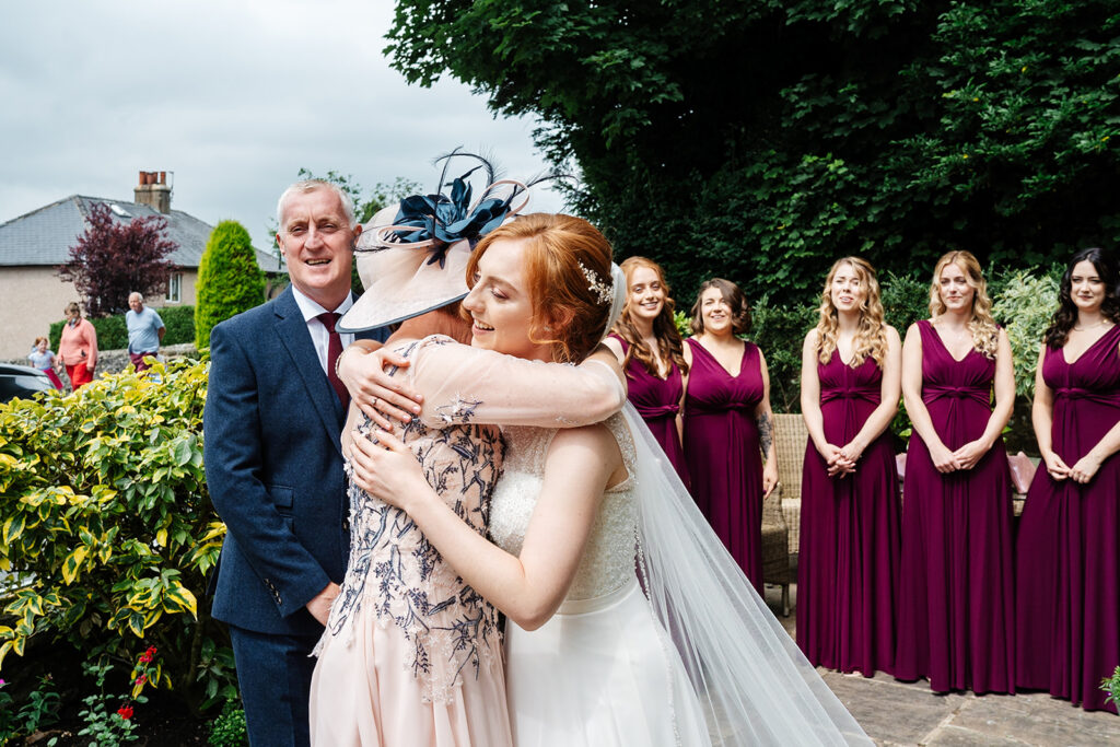 Bride embraces guest at outdoor wedding ceremony scene