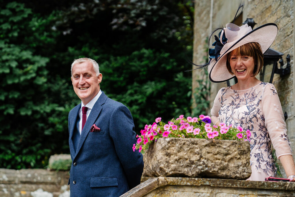 Elegantly dressed couple smiling outdoors with flowers nearby