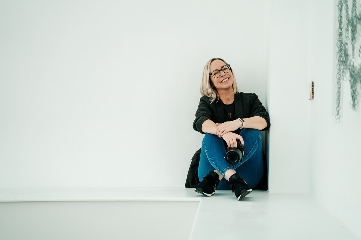 Person sitting in a bright room holding a camera smiling