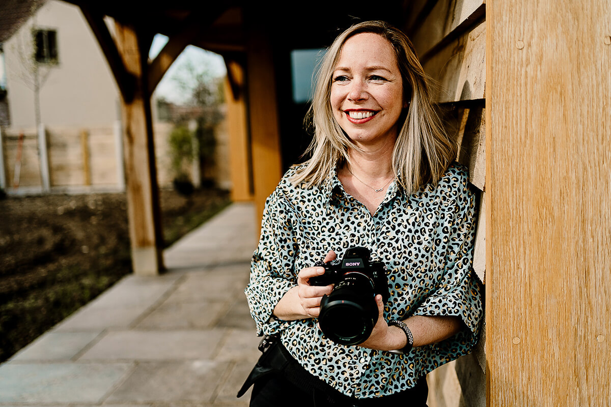 Woman smiling while holding a camera outdoors