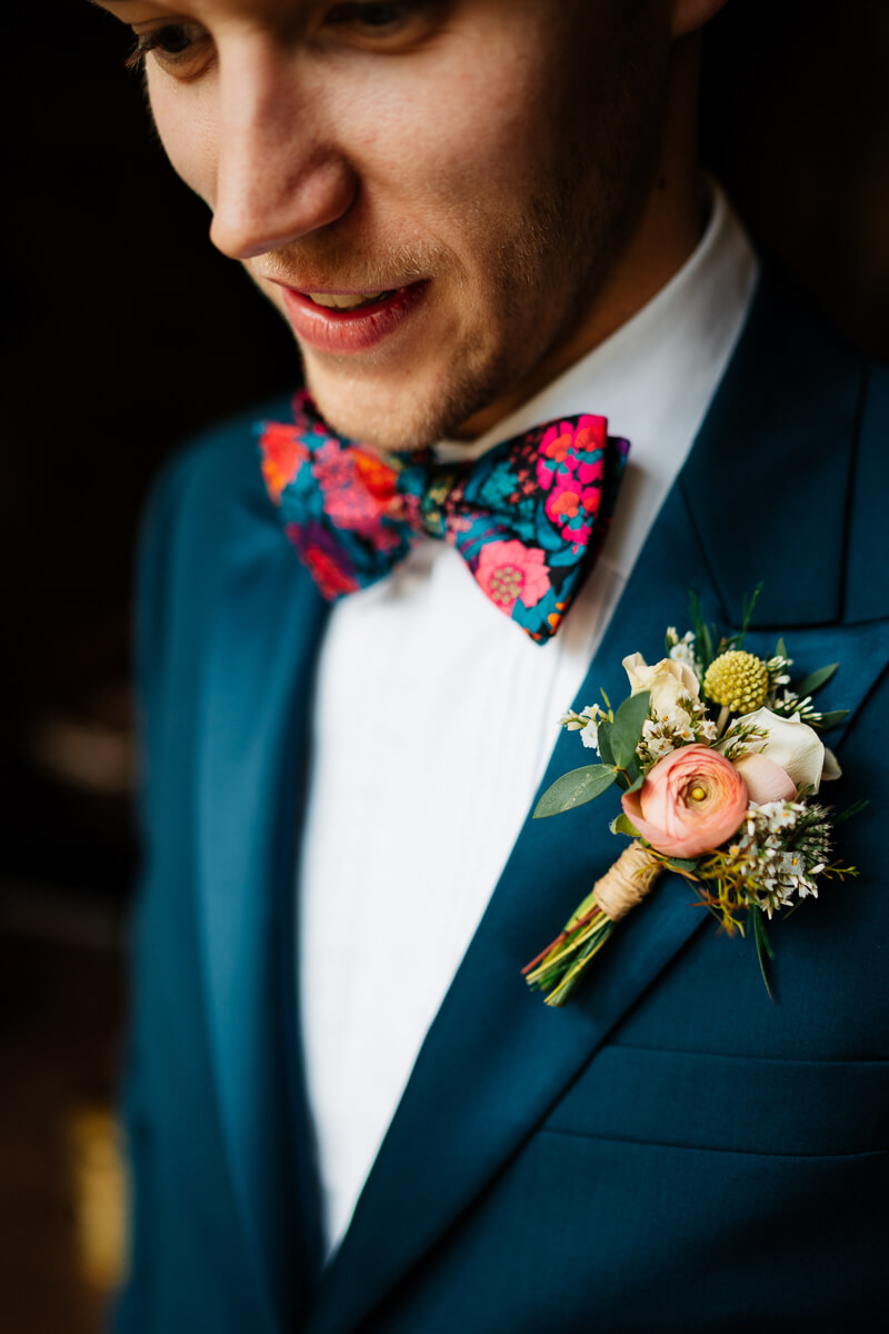 Man in blue suit with floral bowtie and boutonniere