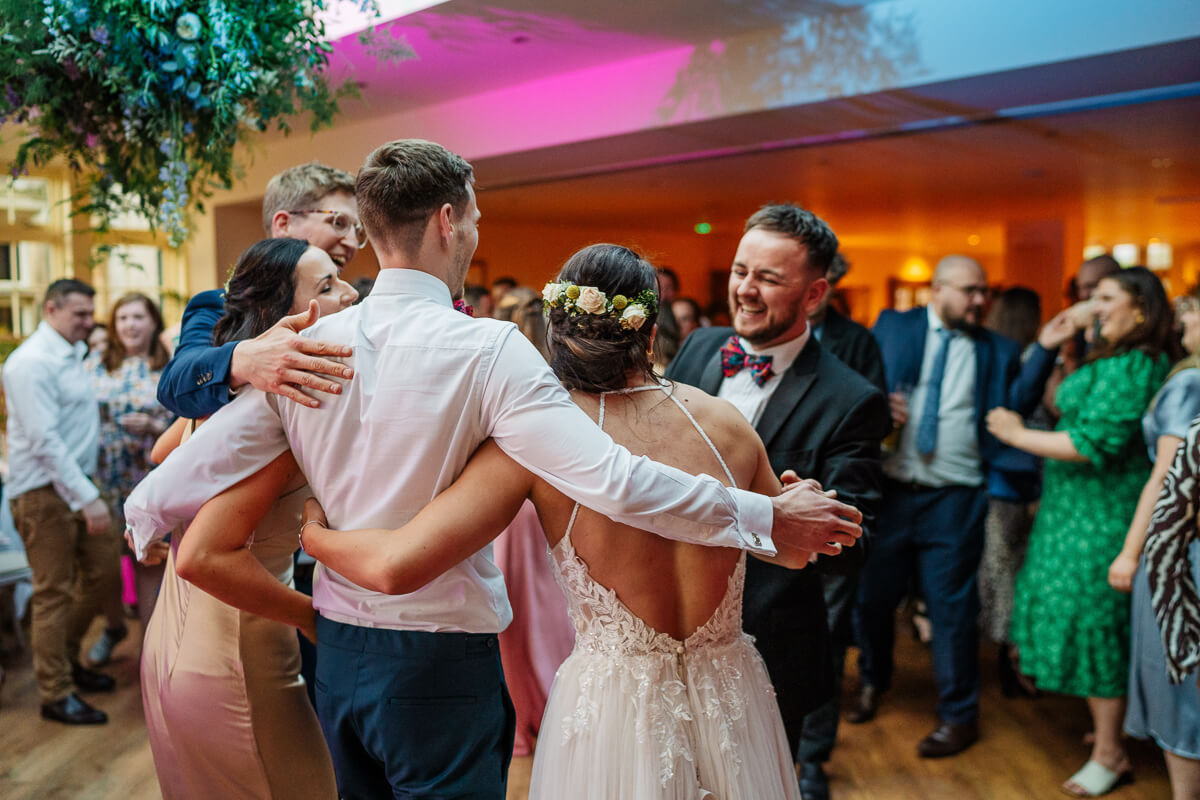Wedding guests joyfully dancing and embracing at a reception