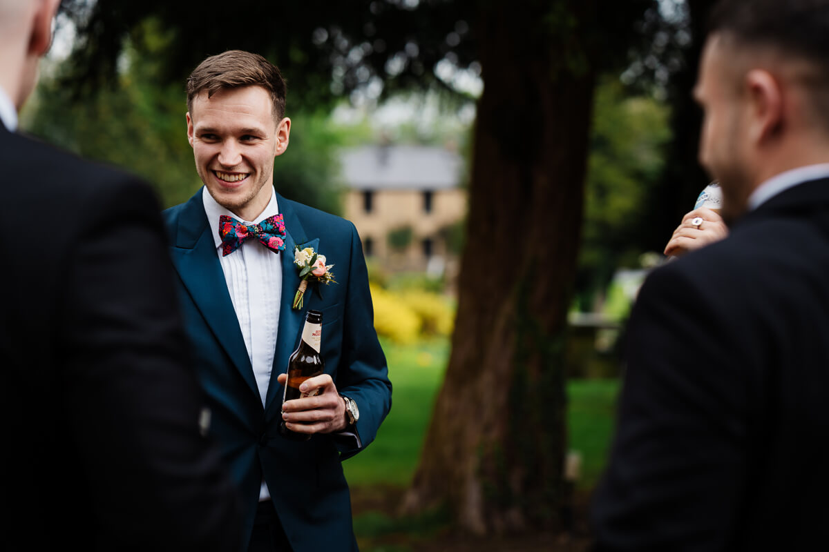 Man in a suit smiling and holding a drink outdoors