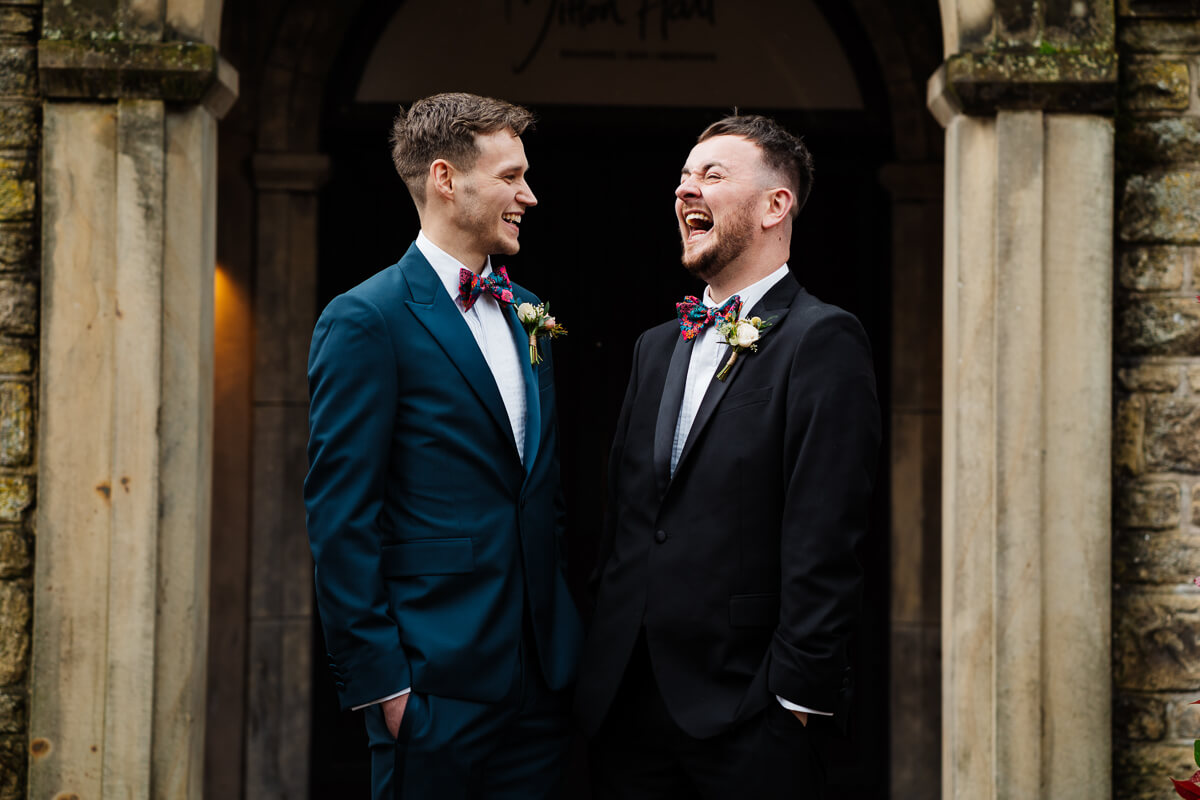 Two grooms laughing joyfully at a wedding ceremony