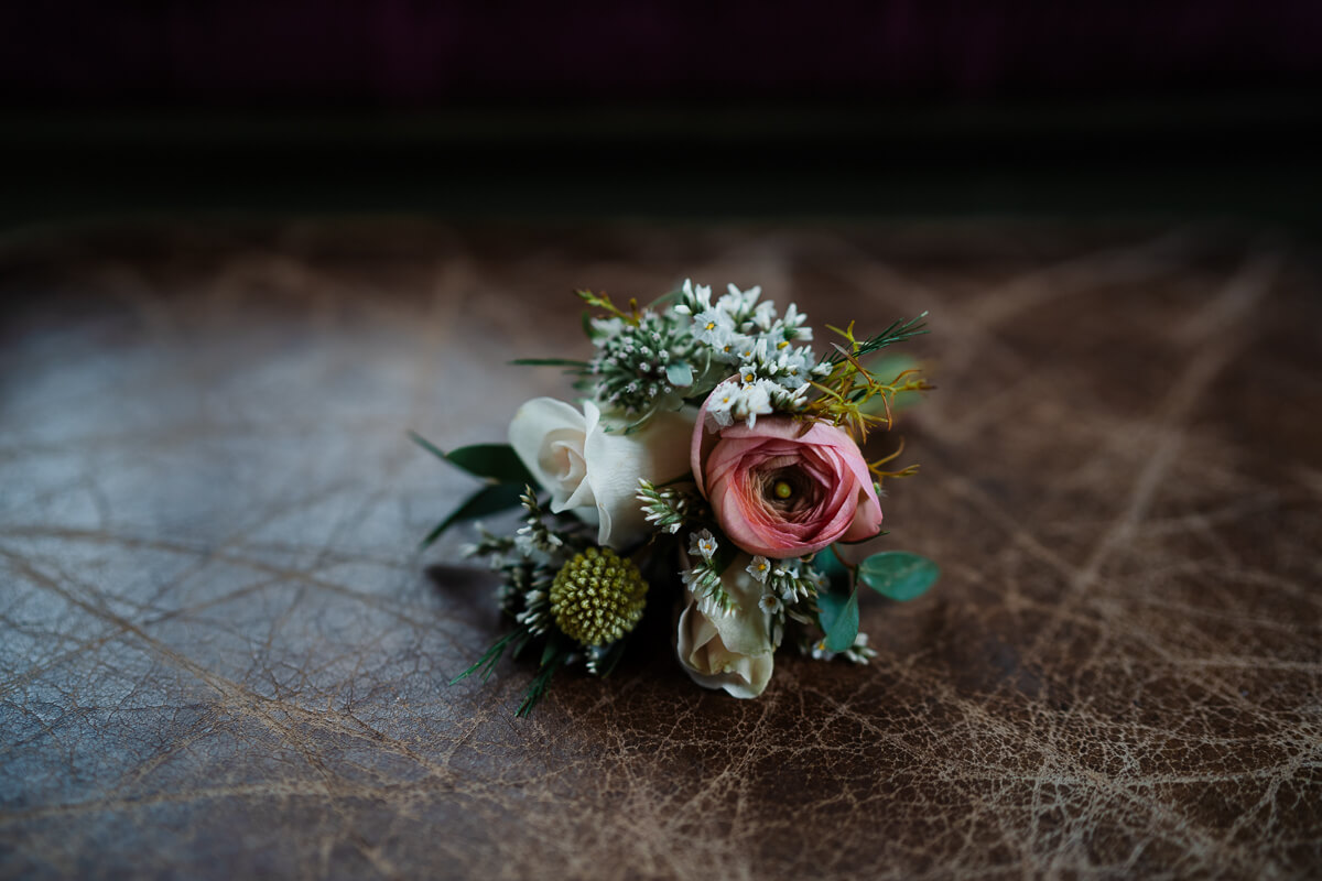 Elegant pink and white floral boutonniere on leather surface