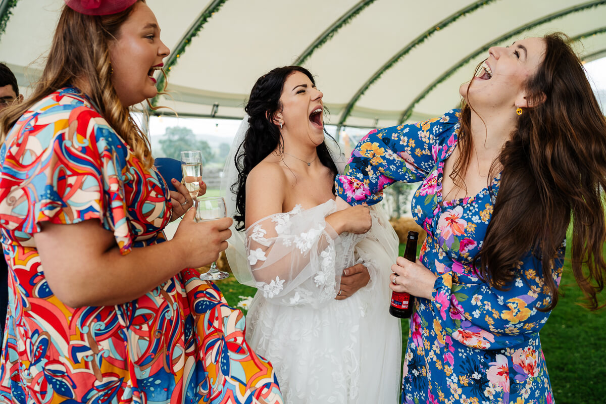 Women in colourful dresses laughing at a festive outdoor event