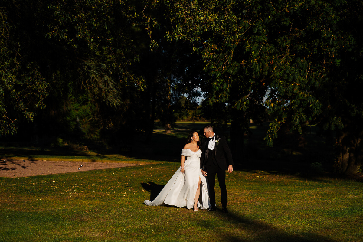 Bride and groom smiling in sunlit garden setting