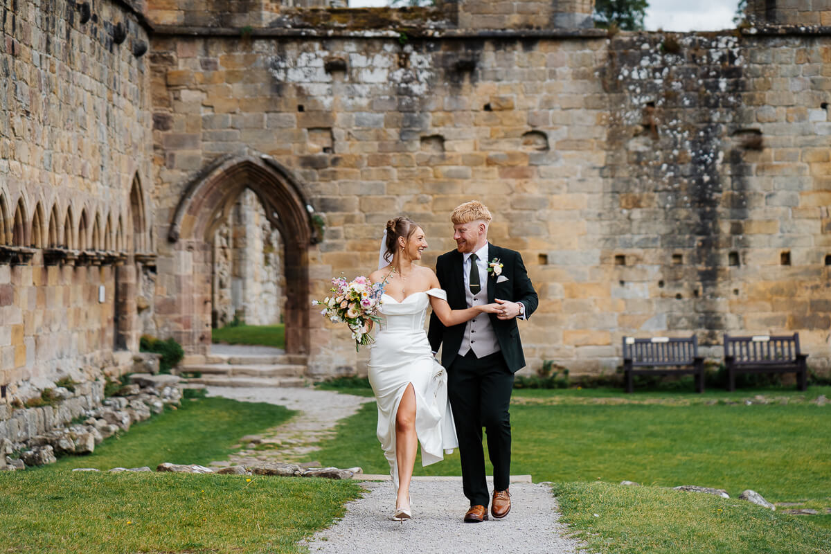 Bride and groom walking happily at historic stone venue