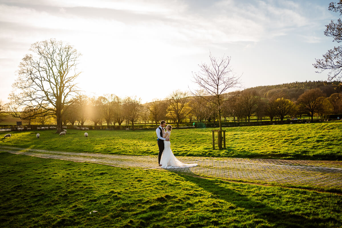 Bride and groom walking in lush countryside at sunset
