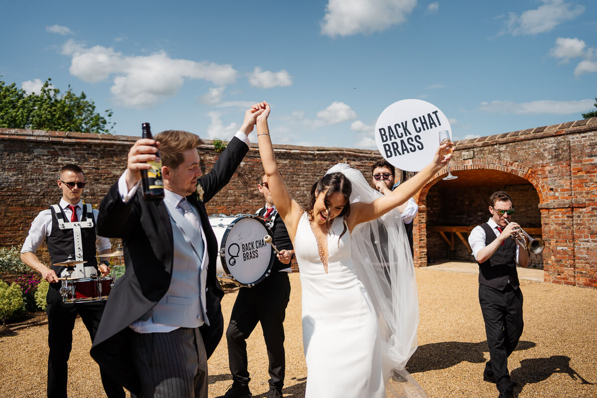Bride and groom celebrating with live brass band outdoors