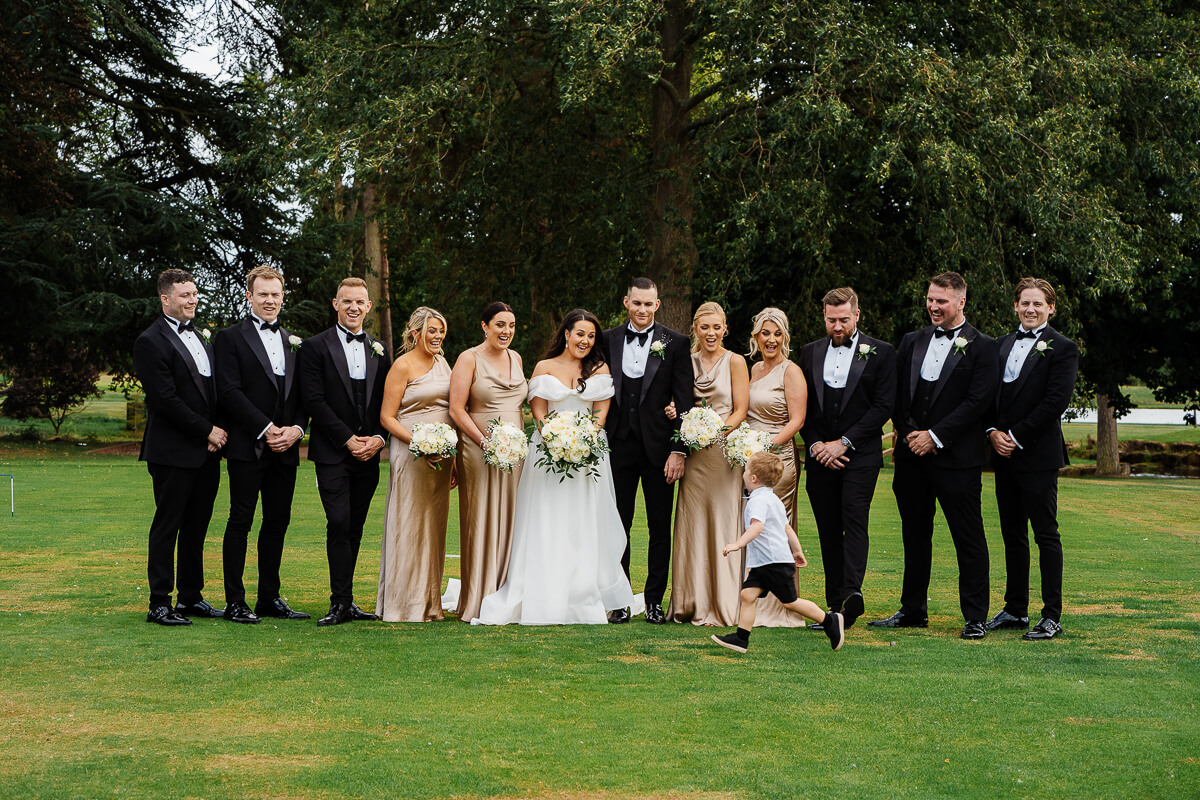 Wedding party posing elegantly outdoors on a lush green lawn