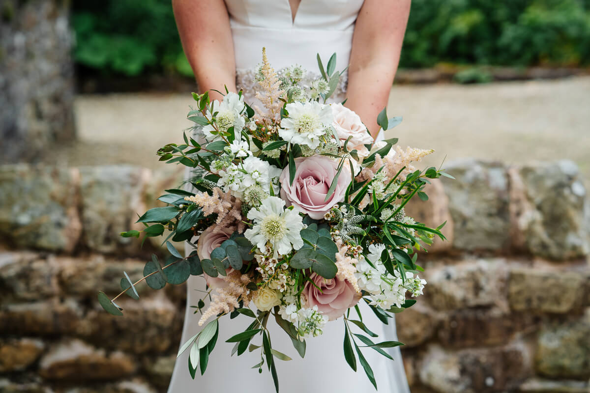 Bride holding a beautiful pastel flower bouquet on wedding day
