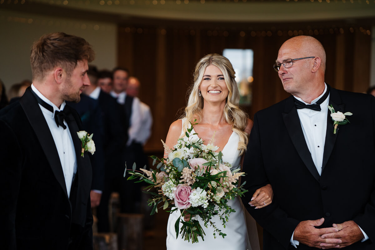 Bride walking down the aisle with father at wedding ceremony