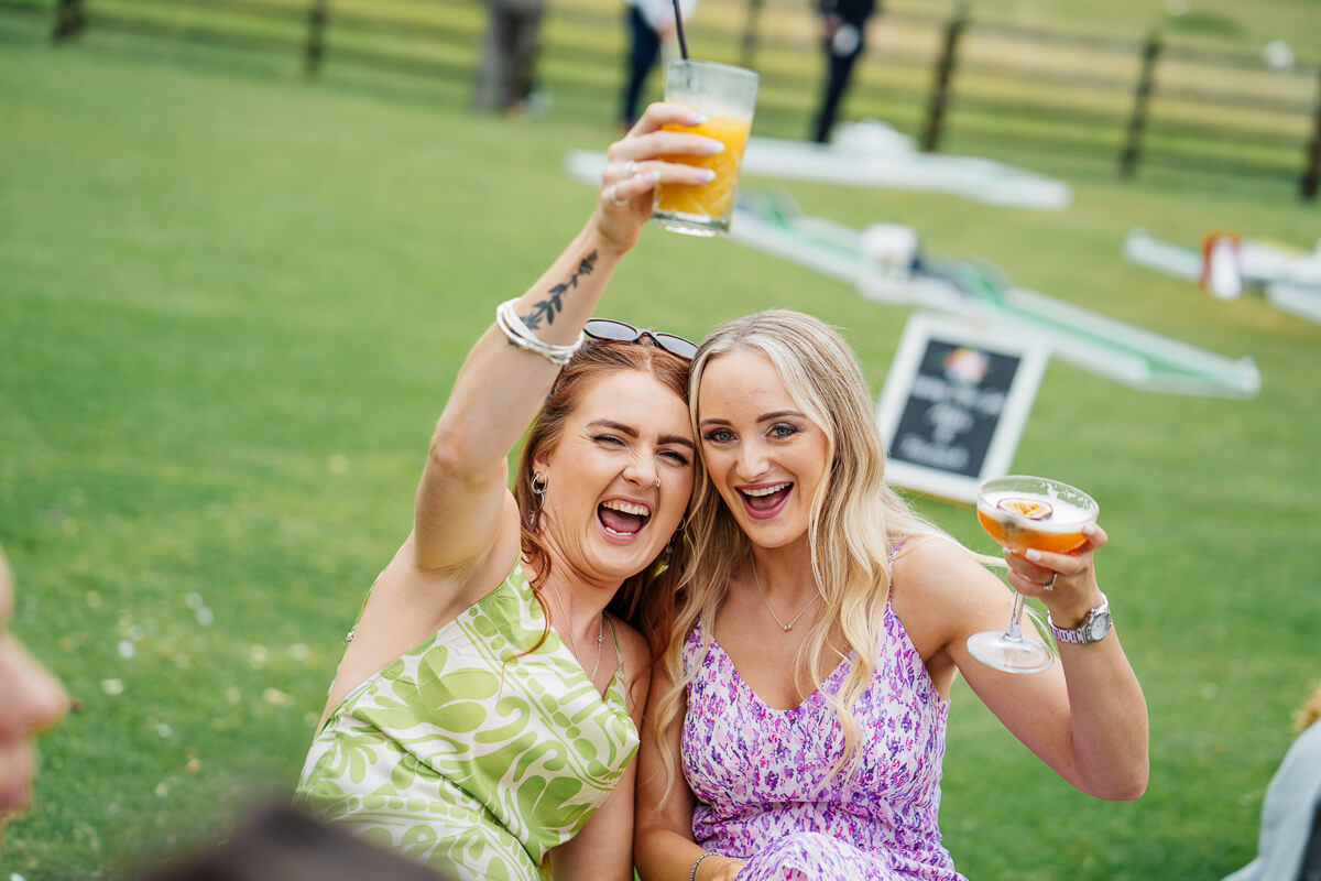 Women enjoying outdoor event with drinks in hand