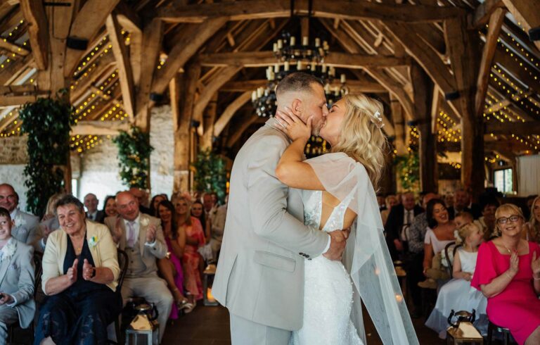 Bride and groom share a kiss at rustic indoor wedding ceremony