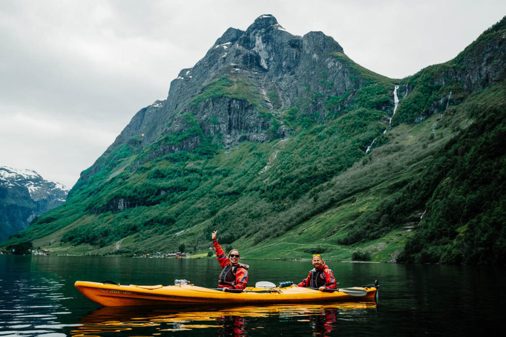 Two people kayaking on a scenic lake with mountain backdrop