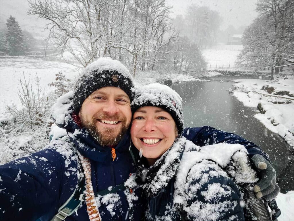 Couple smiling in a snowy winter landscape by a tranquil river