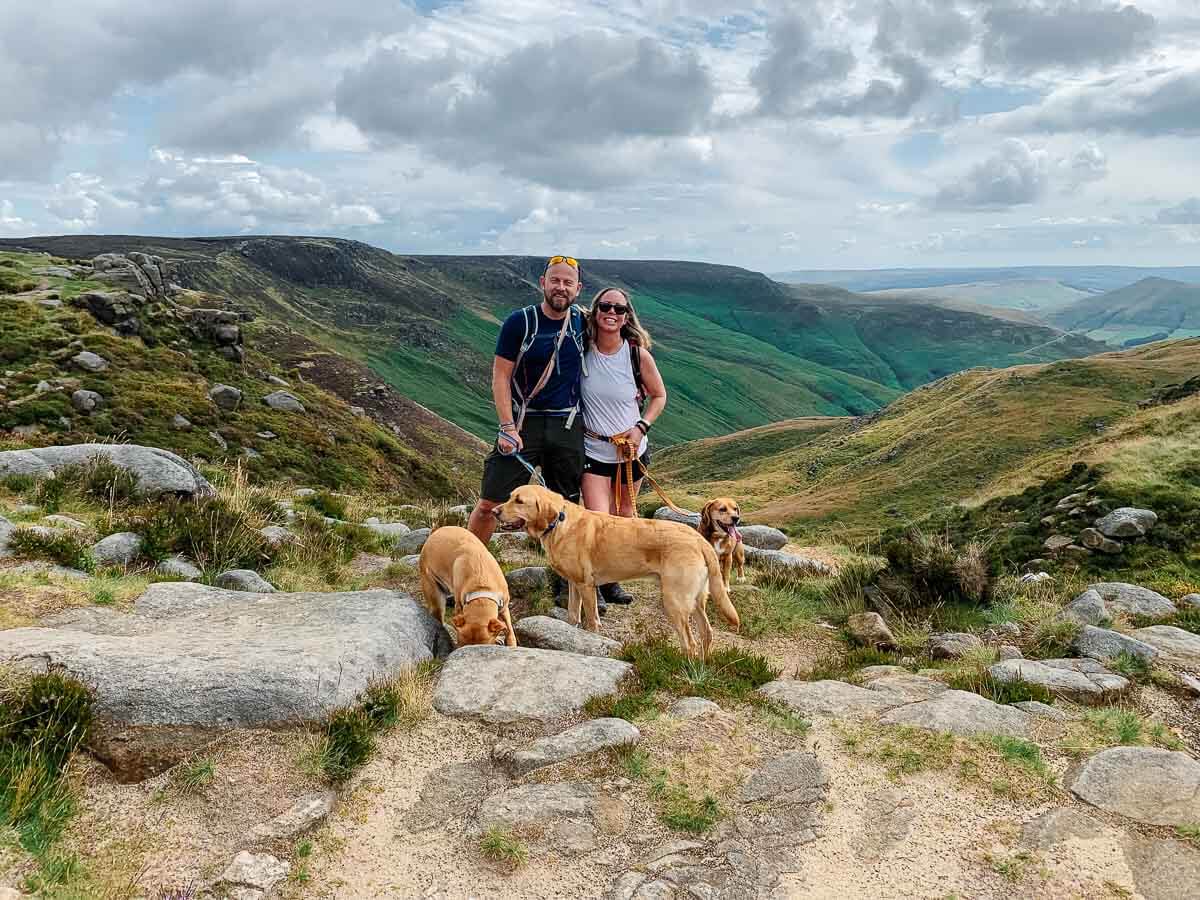 Couple hiking with dogs in scenic mountainous landscape